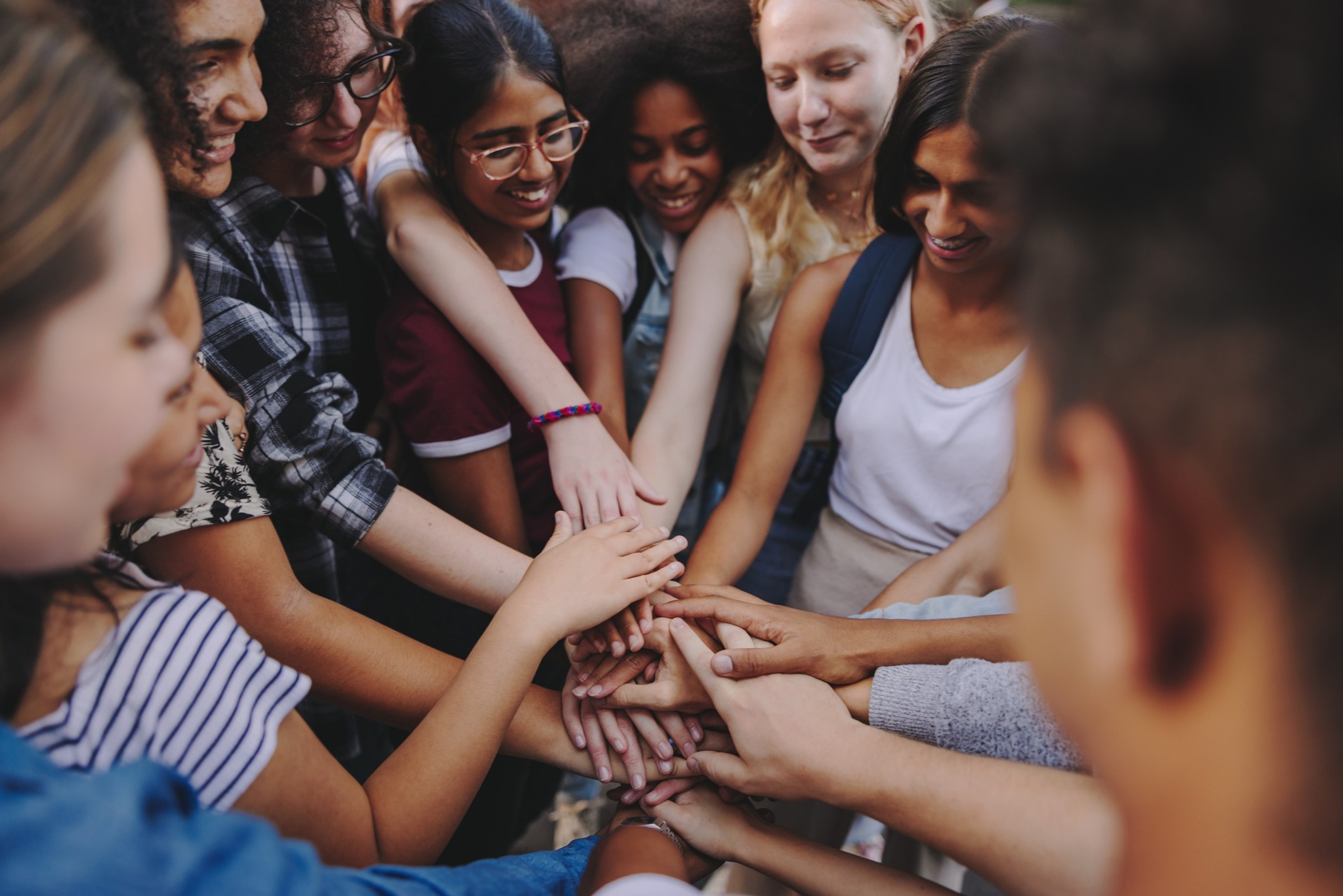 Teenagers in a group with all of their hands in the middle